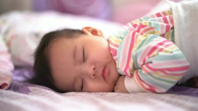 一个4个月的亚洲女婴在家床上睡觉