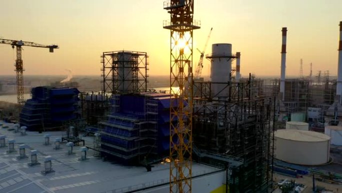 日落时分，联合循环发电厂塔式起重机和冷却塔的施工现场鸟瞰图