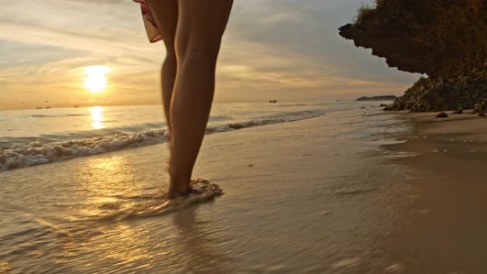 日落时在海滩上散步的拉女人