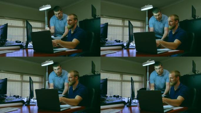 男性机器人工程师在4k桌上讨论笔记本电脑