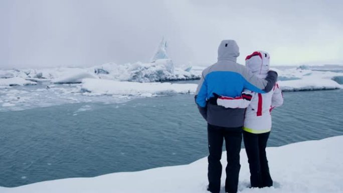 夫妇女士在冰岛Jokulsarlon泻湖的海洋上看着冰山