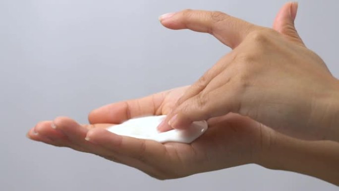 手部触摸奶油保湿霜的特写。
