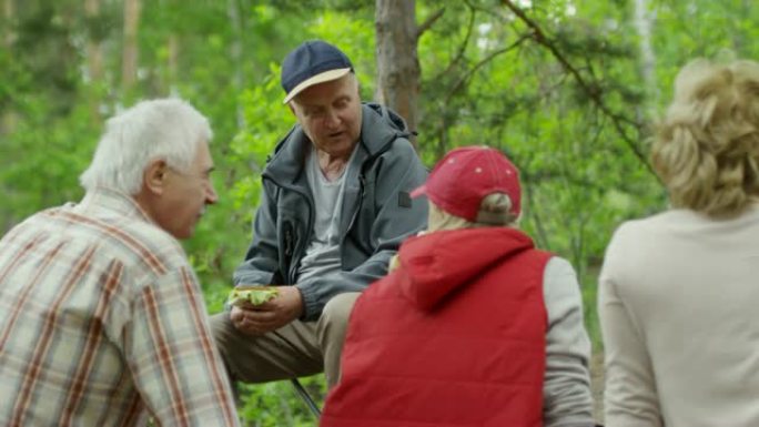老年徒步旅行者在森林里吃三明治