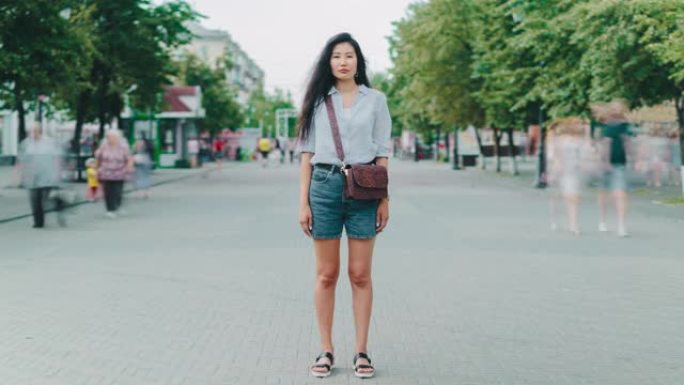 站在城市步行街上看着相机的亚洲女士的延时