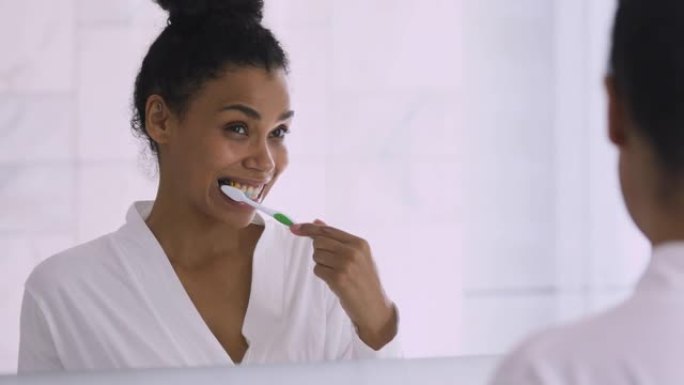 快乐健康的年轻非洲妇女刷牙照镜子