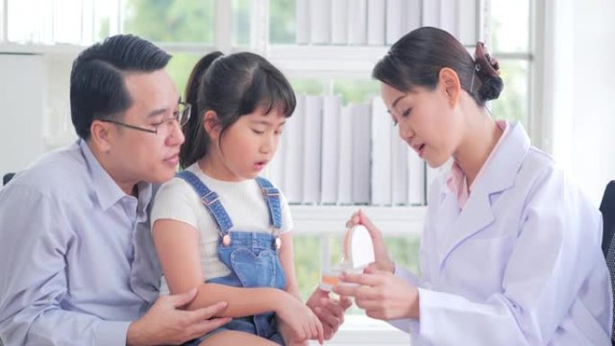 医学，牙科和保健概念-牙医在牙科诊所向儿童患者和她的父亲展示牙齿模型。中国和香港的医疗系统