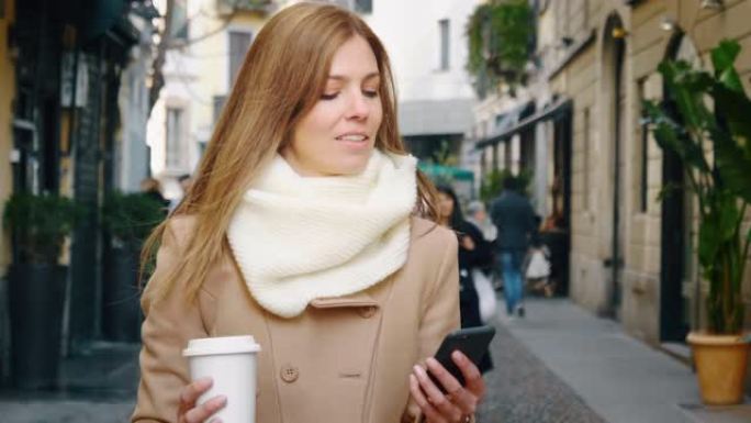 一位穿着优雅的职业女性在喝美国咖啡的同时走在城市的街道上