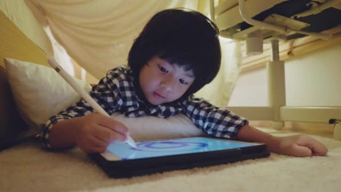 小男孩在家里的小帐篷里使用数字平板电脑