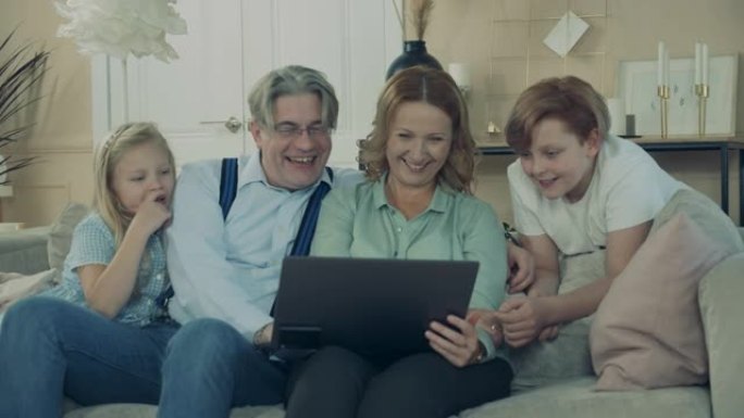 奶奶和爷爷和孙子孙女和笔记本电脑玩得很开心