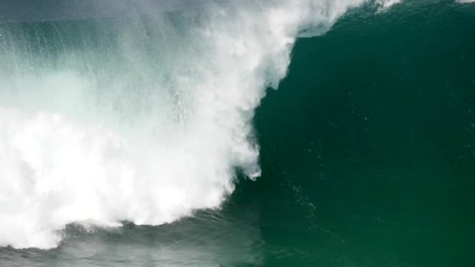 巨大的绿松石色海浪压在海岸上，变成了大量的白色泡沫 (海浮渣)。慢动作镜头