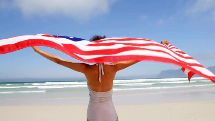 女人站在海边挥舞着美国国旗。在海滩4k