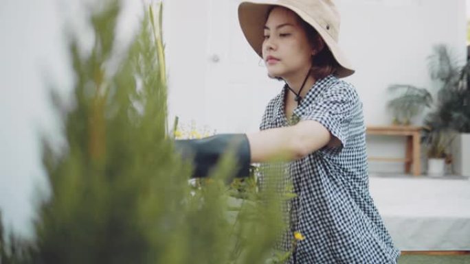 亚洲女性在周末在家的前院园艺。