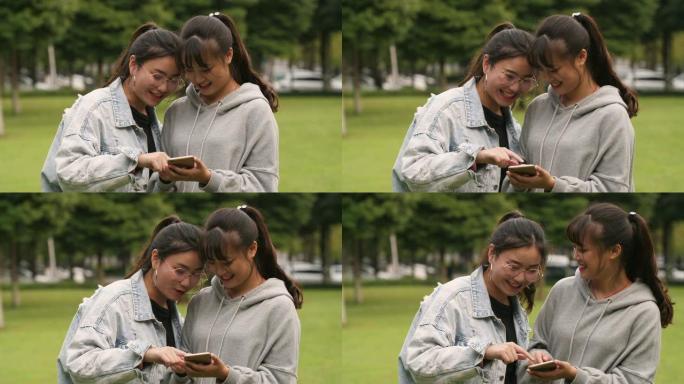 两名亚裔女大学生在校园内使用手机