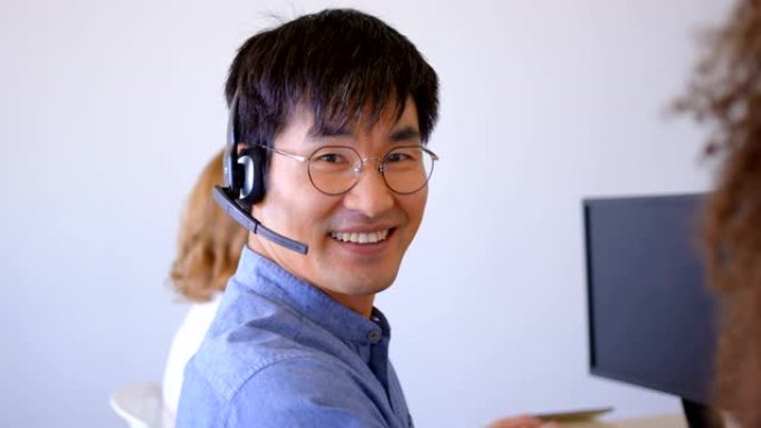 年轻的亚洲男性客户销售主管在现代办公室4k上谈论耳机