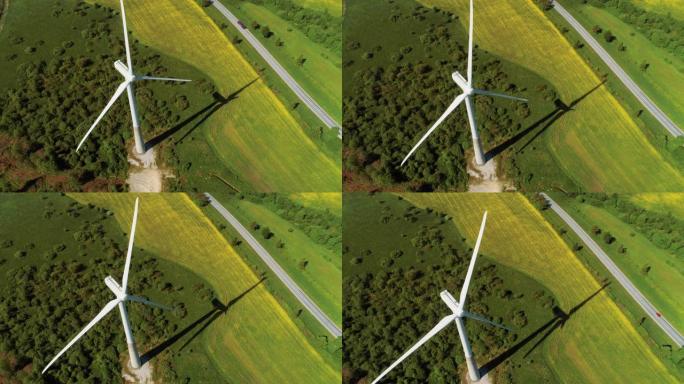 在绿色森林和田野的农村地区，风力涡轮机的空中无人机镜头。风车生产清洁的可再生能源。