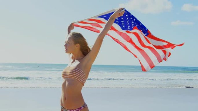 女子在4k海滩上举着美国国旗
