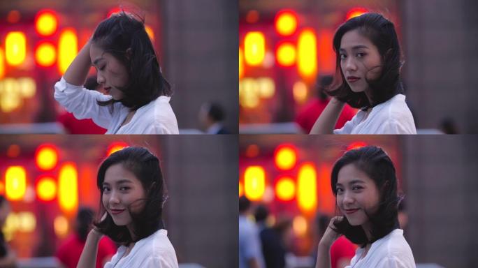 迷人的年轻亚洲女子在城市夜晚对着镜头微笑