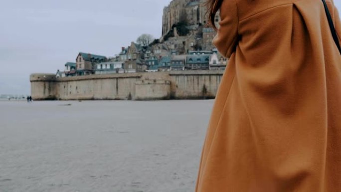 穿着优雅外套的时尚博主女人走向圣米歇尔城堡地标慢动作的后视特写
