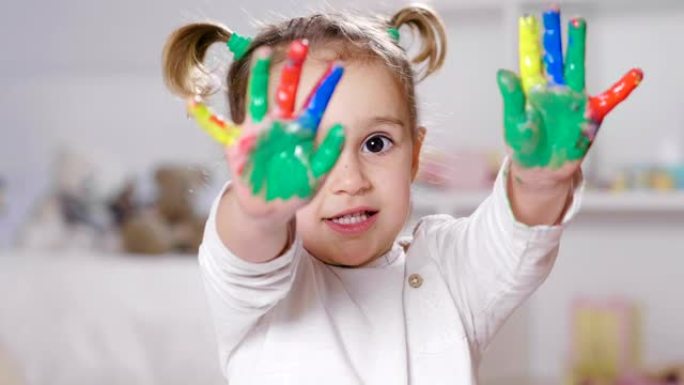 卧室里一个小女孩的肖像，显示她的手都被油漆着色。