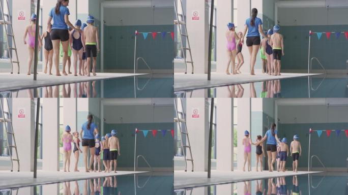 女教练沿着室内游泳池的边缘在游泳课上散步