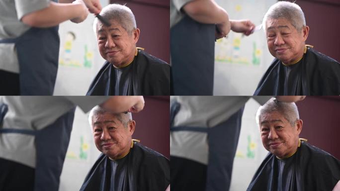 由于旅行禁令，一名亚洲华裔中年妇女正在厨房为父亲剪头发和修剪头发