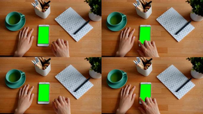 女性手触摸桌子上绿色色度键智能手机屏幕的特写