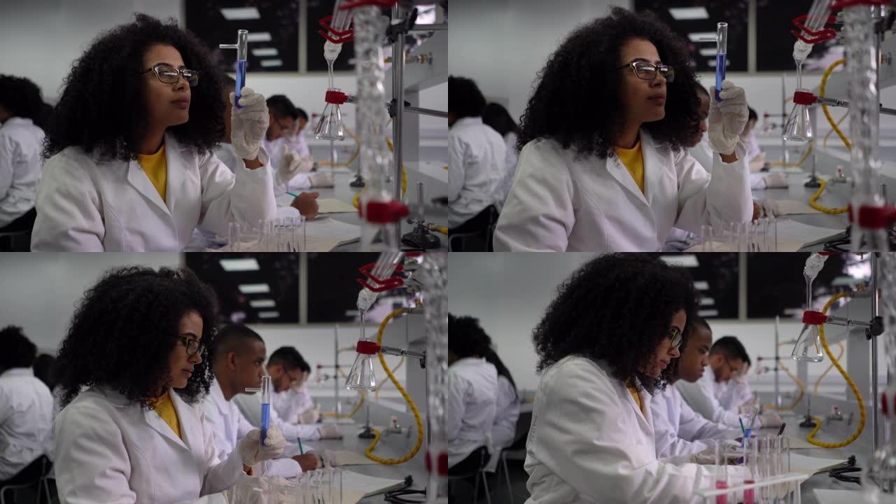 漂亮的黑人学生在化学课上在记事本上做笔记时非常近距离地看着试管中的液体
