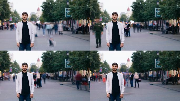 长着胡子的帅哥看着镜头，微笑着站在市中心的街道上，然后在男人和女人靠近他的时候退后一步。