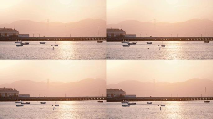 美丽的背景拍摄浪漫的迷雾旧金山日落码头与船和鸟，阳光反射在海水中。