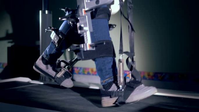金属机器帮助一个人走路，侧视图。