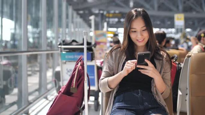亚洲妇女在机场使用社交媒体进行交流