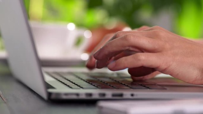 女性手指按下笔记本电脑的按钮，女性打字，在家或办公室工作。UHD滑动镜头