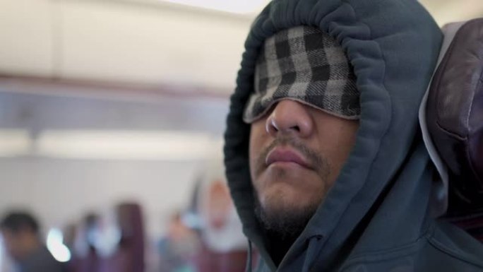 特写镜头男子戴着眼罩睡眠面罩在飞机上睡觉