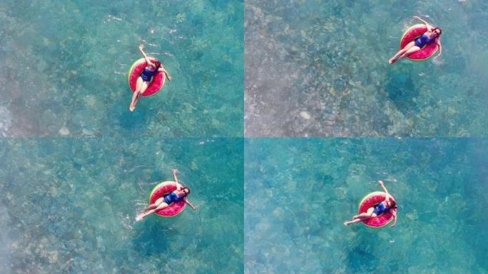 一个女人漂浮在海上的橡胶圈上。美丽的年轻女子放松。