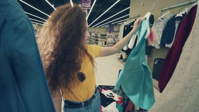 开朗的女士正在商店里把衣服放进手提箱里