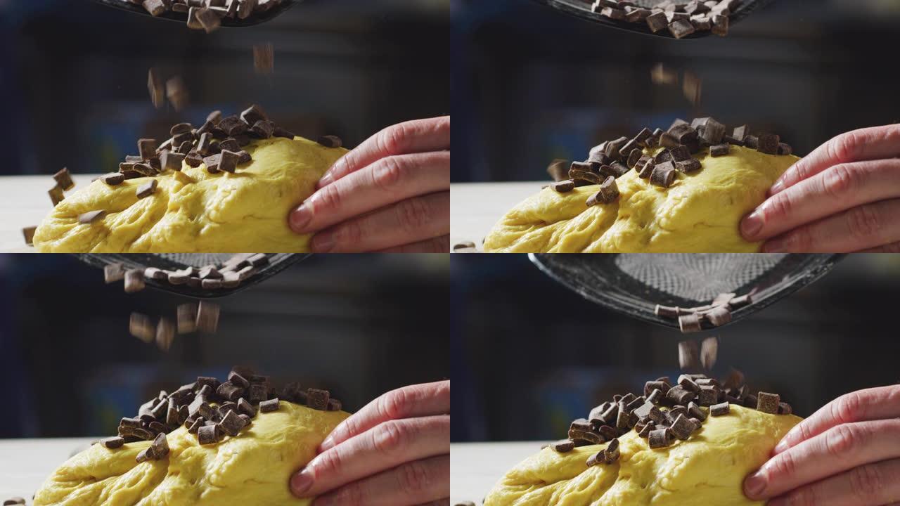 面包师的慢动作是将巧克力块放入面团中以准备甜点。
