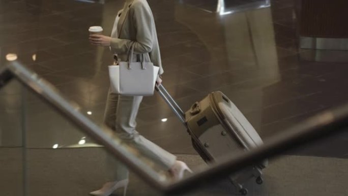 女商人带着行李和咖啡走进酒店