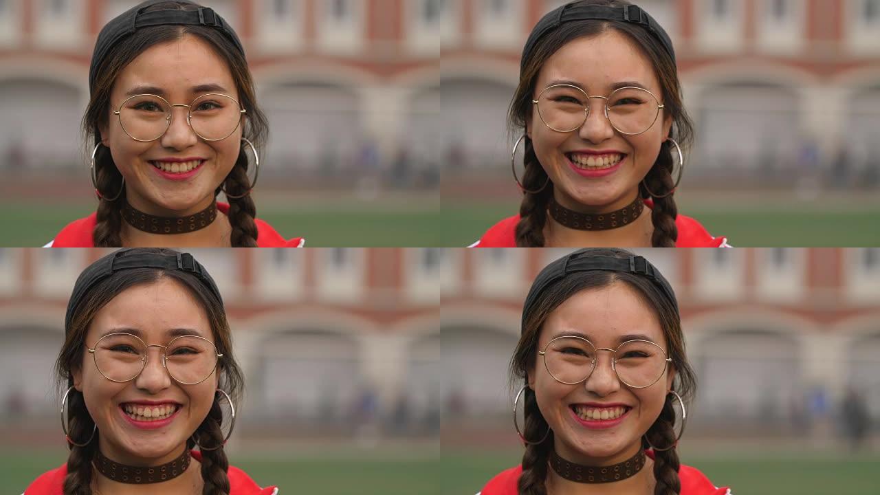 一名年轻的亚洲大学生女孩在校园户外相机微笑的特写镜头，4k