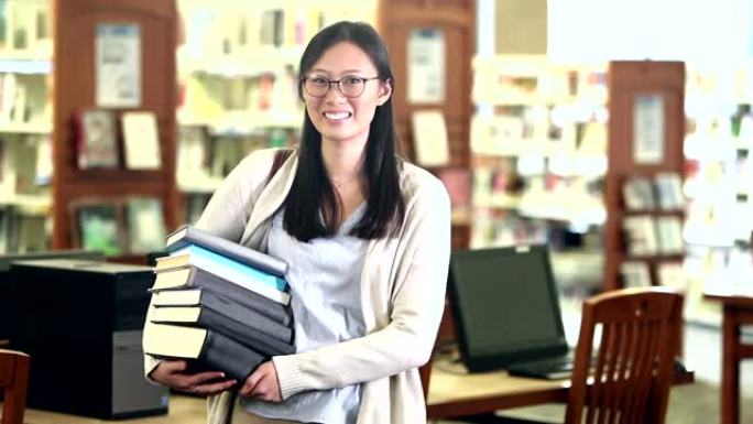 年轻的韩国妇女在图书馆里背着一堆书
