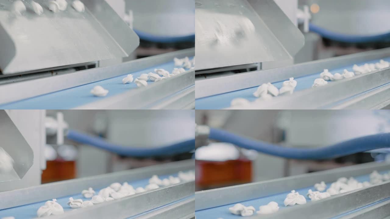 关闭饺子工厂自动机器生产过程的镜头。新鲜的生水球落在传送带上。在食品工厂运行的工业机械。