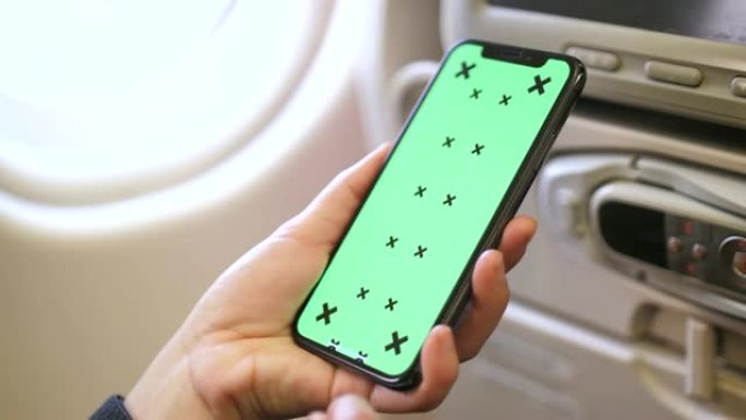 特写女人在飞机上使用带有绿屏的智能手机