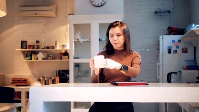 年轻女子正在用合成手从杯子里喝水