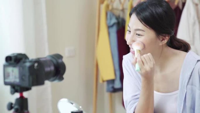 慢动作: 亚洲年轻女性博客作者在家中录制带有化妆化妆品的vlog视频。有影响力的女人在线直播病毒。