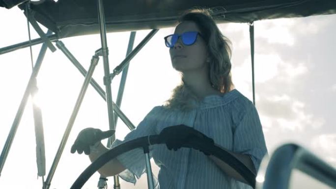 一个女孩拿着舵驾驶游艇。海上旅行，女士船长的暑假。