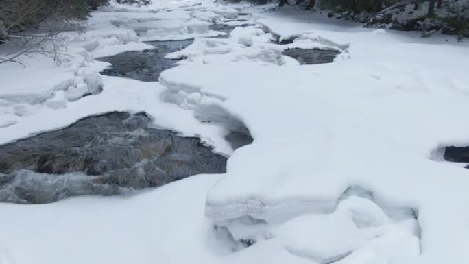 特写: 森林溪流在穿越白雪皑皑的风景时飞溅。