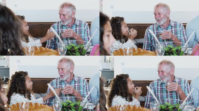 多代家庭聚会在家用餐时，祖父和孙女敬酒
