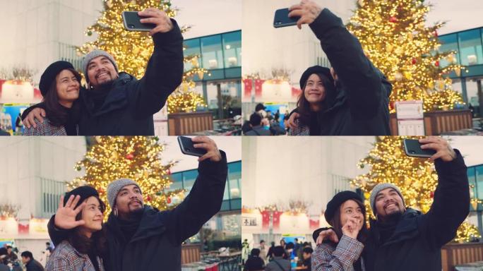 快乐的亚洲情侣在日本圣诞市场自拍。