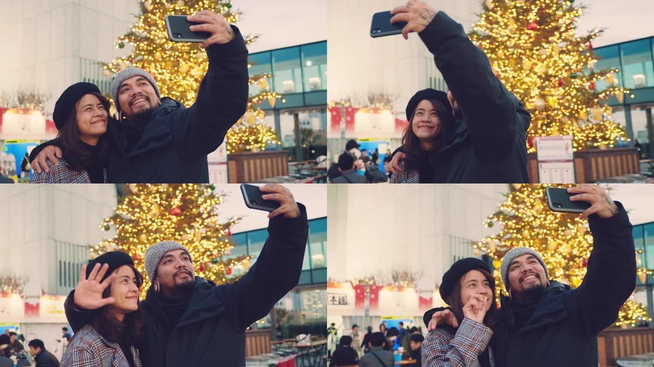 快乐的亚洲情侣在日本圣诞市场自拍。