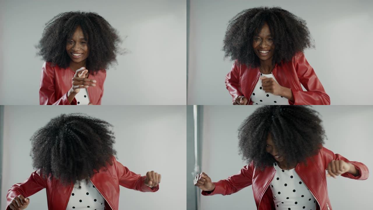 迷人的黑人女孩，郁郁葱葱的卷发摆姿势拍摄时尚杂志照片。美丽的女孩嬉戏地微笑，跳舞，玩面部表情。在工作