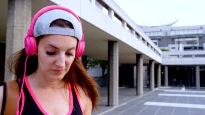女街舞演员在城市4k的耳机上听音乐